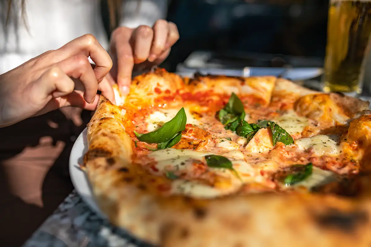 En ny bakt pizza äts med fingrarna.